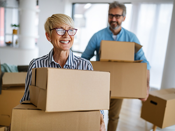 Happy senior couple lift boxes while moving into new home