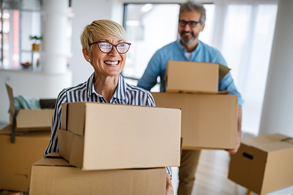 Smiling senior couple lift boxes while moving into new home