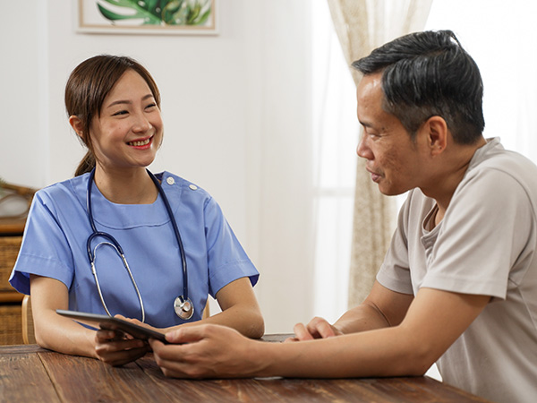 Nurse shows elderly man medication information on ipad