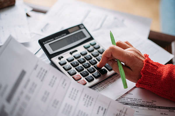 The hands of an elderly woman with a calculator and paperwork