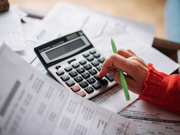 The hands of an elderly woman with a calculator and paperwork