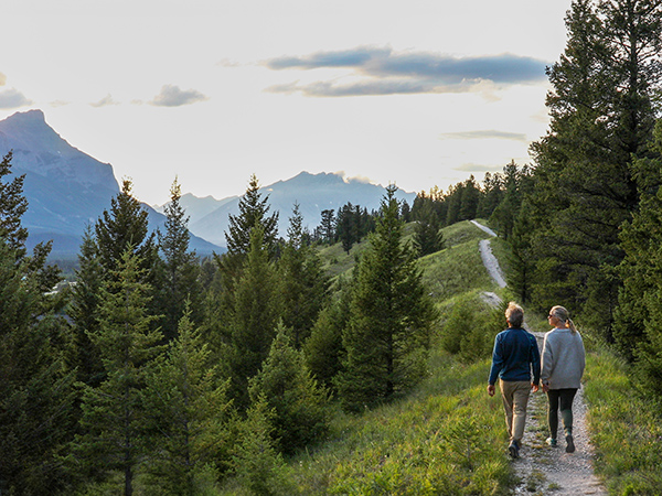 Senior couple hike on mountainous trail at sunrise